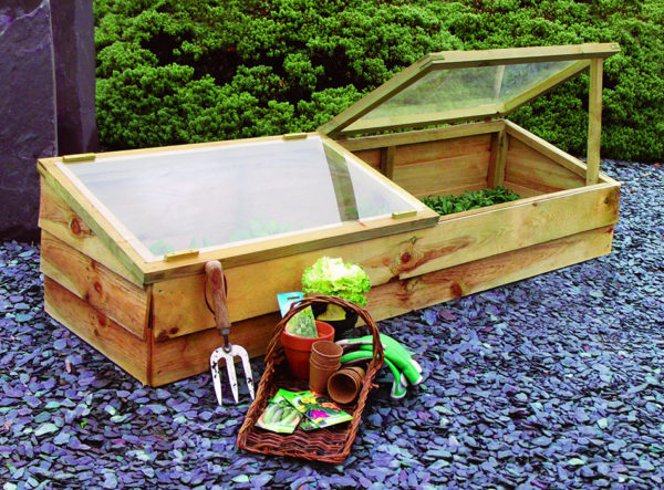 A cold frame box with garden supplies sitting next to it